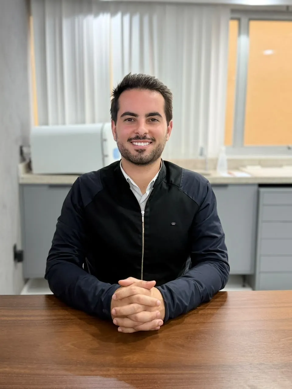 Dr. Victor Lopes sentado à mesa em seu consultório